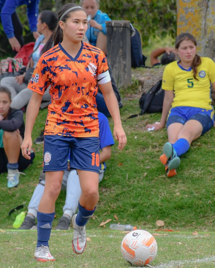 A young woman soccer player stands on the field during a match, ready to play.